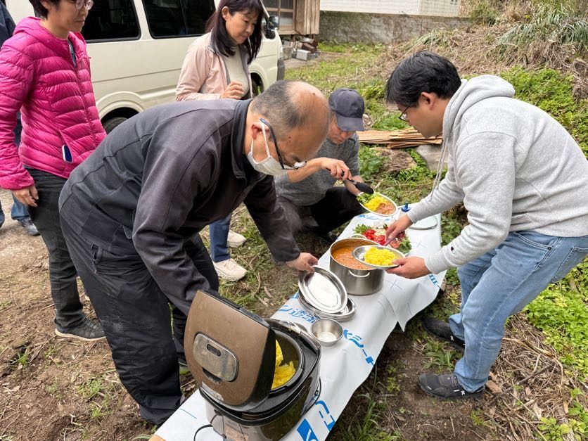 屋外でみんなで食事を囲む交流の様子